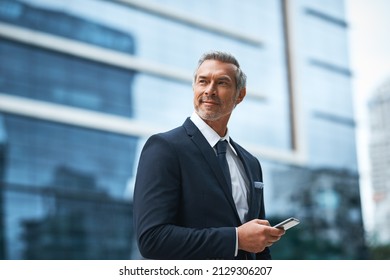 Hard work, determination, persistence creates a boss. Shot of a handsome mature businessman in corporate attire using a cellphone outside outside during the day. - Powered by Shutterstock