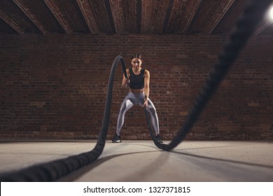 Hard work of female crossfit instructor proves that training ropes are a very dynamic workout that accelerates athlete's pulse while strengthening his body, low angle panoramic shot. - Shutterstock ID 1327371815