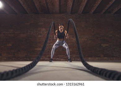 Hard work of female instructor proves that training ropes are a very dynamic workout that accelerates athlete's pulse while strengthening his body, low angle panoramic shot. - Shutterstock ID 1315162961