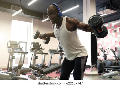 Hard Workout. Muscular Black Man Doing Exercises With Dumbbells For Back At Gym