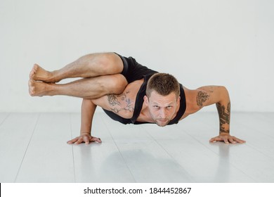 Hard Yoga Pose. A Man Stands On His Arms And Legs In The Air.