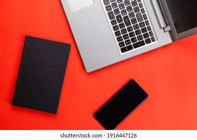 Hardcover Book, Phone, Laptop On A Red Background.Flat Lay.  No People.