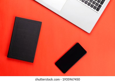 Hardcover Book, Phone, Laptop On A Red Background.Flat Lay.  No People.