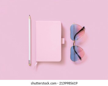 Hardcover textbook, heart sunglases and pensil on pink. Hardcover notebook mockup flat lay.  Femminine girly and Travel concept 
