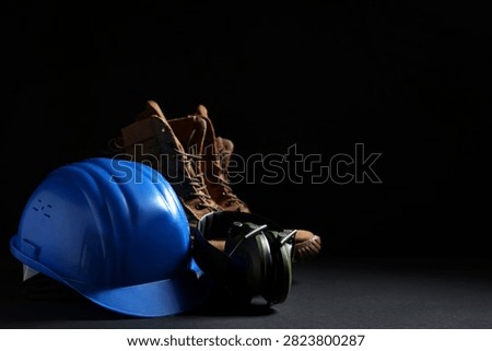 Hardhat, boots and construction tools on black background, closeup