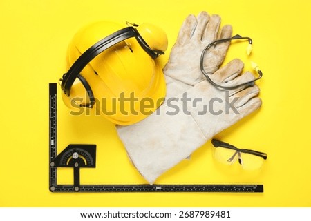 Hardhat, construction tools and gloves on yellow background