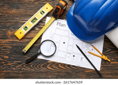 Hardhat, house plan and construction tools on wooden background