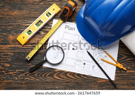 Hardhat, house plan and construction tools on wooden background