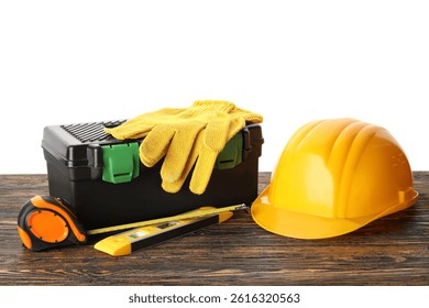 Hardhat, toolbox and construction tools on wooden table against white background