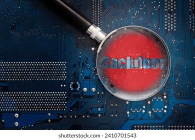 Hardware backdoor chip on a printed circuit board. A look through a magnifying glass with a red warning. Concept of computer security and searching for hardware bookmarks.