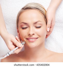 Hardware cosmetology. Closeup portrait of female face with closed eyes getting microdermabrasion procedure in a beauty parlour.