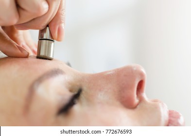 Hardware cosmetology. Closeup portrait of female face with closed eyes getting microdermabrasion procedure in a beauty parlour. Procedure of Microdermabrasion