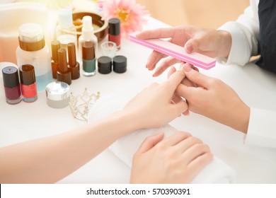 Hardware Manicure In A Beauty Salon. Asian Chinese Manicurist Is Applying Nail File Drill To Manicure On Female Fingers. Real Salon Spa Background. Beauty And Fashion Concept.