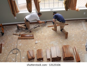 Hardwood Floor Installation - Construction Workers Install A Hardwood Floor Over Oriented Strand Board In A Residence.