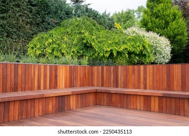 Hardwood timber deck, bench and cladding wood structure with greenery garden view, brown and green natural elements