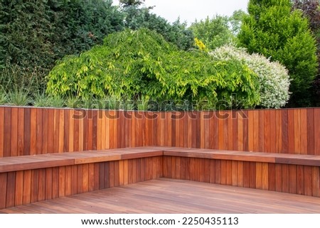 Hardwood timber deck, bench and cladding wood structure with greenery garden view, brown and green natural elements