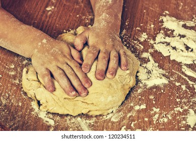 Hardworking children hands make a dough.