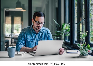 Hardworking company employee, making sure his new office laptop is working. - Shutterstock ID 2144697465