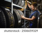 Hardworking experienced worker holding tire and he wants to change it In the tire store. Selective focus on tire.