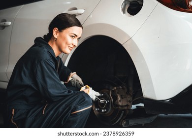 Hardworking female mechanic changing car wheel in auto repair workshop. Automotive service worker changing leaking rubber tire in concept of professional car care and maintenance. Oxus - Powered by Shutterstock