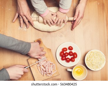 Hard-working hands. Cooking with children. Child and mother hands knead and roll dough with a rolling pin on the table.