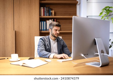 Hardworking male person in elegant suit sitting in company office and working on the computer.