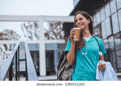 Hardworking mid adult beautiful nurse climbs the stairs to her apartment after a hard day at work. Portrait of happy young female nurse. A female healthcare worker leaving the house in her uniform. - Powered by Shutterstock