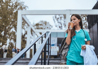 Hardworking mid adult beautiful nurse climbs the stairs to her apartment after a hard day at work. Portrait of happy young female nurse. A female healthcare worker leaving the house in her uniform. - Powered by Shutterstock