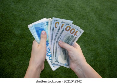 Harish, Israel - August 5 2021: Two woman hands counting many 200 israel shekel and 100 US dollar banknotes. 