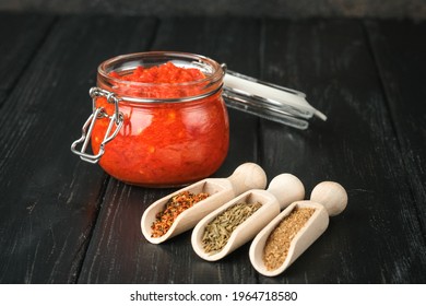 Harissa In A Glass Jar With Spices On A Dark Rustic Background.