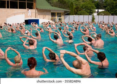 Harkany, Hungary - April 4, 2011: Group of people doing exercises in a thermal pool following a woman trainer's instructions