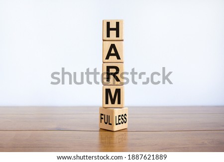 From harmful to harmless. Turned the wooden cube and changed word 'harmful' to 'harmless'. Beautiful wooden table, white background. Business and harmful or harmless concept. Copy space.