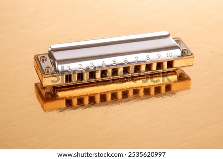 The harmonica lies on a mirrored surface. Classical musical wind instrument.