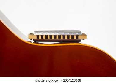 The harmonica rests on the body of a classical guitar. Classical musical wind instrument.