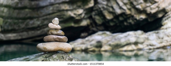 Harmony, balance and simplicity concept. A stone pyramid on the background of river water. Simple poise pebbles, rock zen sculpture, a tower from river stones