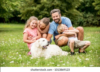 Harmony And Luck In The Family Concept With Parents And Kids And Dog In The Park