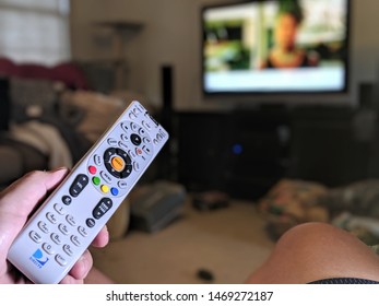 Harrisburg, PA - August 3rd, 2019 - Man Points Directv Remote Towards Tv In Living Room Scene.