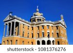 Harrison County Courthouse in Marshall, Texas receives a facelift.  Worker standing on a tall ladder repaints the trim on upper story windows.