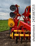 harrow-cultivator standing folded for transportation near a field, agricultural technologies