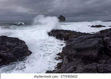 The harsh Icelandic coast with big waves beating against black rocks on a cloudy evening in the West of Iceland - Shutterstock ID 1779303653