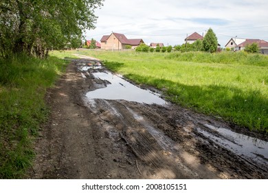 The harsh landscape nature and road through the fields for the off-road SUV with puddles and mud. Spring background. The road washed out by the rains with traces of wheel slip, slush and mud