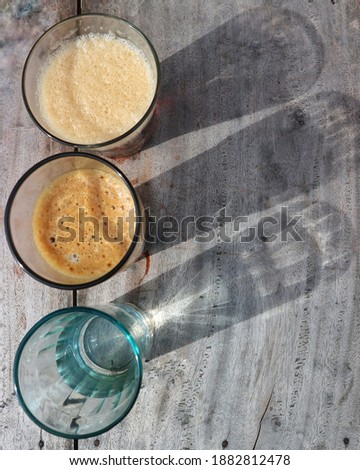 The harsh shadows of three glasses on a wooden table. Selective focus