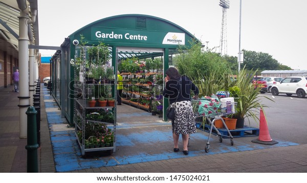 Hartlepool / Great Britain - August\
1, 2019 : Outside entrance to detached small garden centre retail\
area in supermarket car park selling plants with\
customers