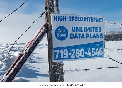 Hartsel. CO / USA - February 11, 2020: An Advertisement Sign For Rural Areas High Speed Internet Unlimited Data Plans Posted On An Old Fence Post In Winter Snow.