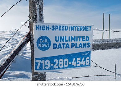 Hartsel. CO / USA - February 11, 2020: An Advertisement Sign For Rural Areas High Speed Internet Unlimited Data Plans Posted On An Old Fence Post In Winter Snow.