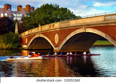 Harvard University crew team in a scull going under the Weeks Bridge on the Charles River.  Beautiful golden morning light and reflections on the water.