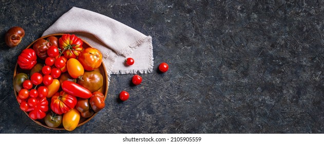 The harvest of assorted tomatoes, banner. Colorful organic tomatoes on a large dish. Tomatoes different varieties. Top view