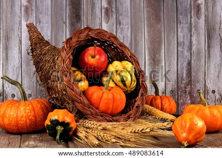 Harvest cornucopia with pumpkins, apples and gourds on rustic wood background