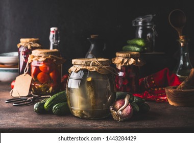 Harvest Preserve Concept. Glass Jars With Fermented, Pickled And Canned Vegetables And Fruits On Dark Rustic Kitchen Table. Conservation Of Farm Organic Seasonal Harvest. Healthy Homemade Food