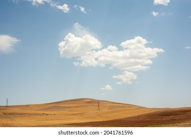 harvested Wheat field on the hill with blue and partly cloudy sky in Kurdistan province, iran
